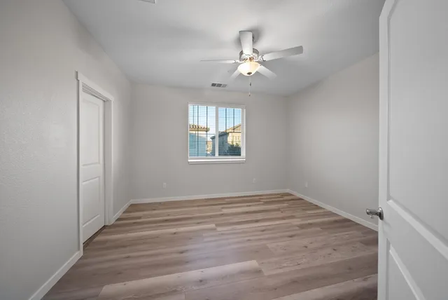 a view of an empty room with chandelier fan and fire place