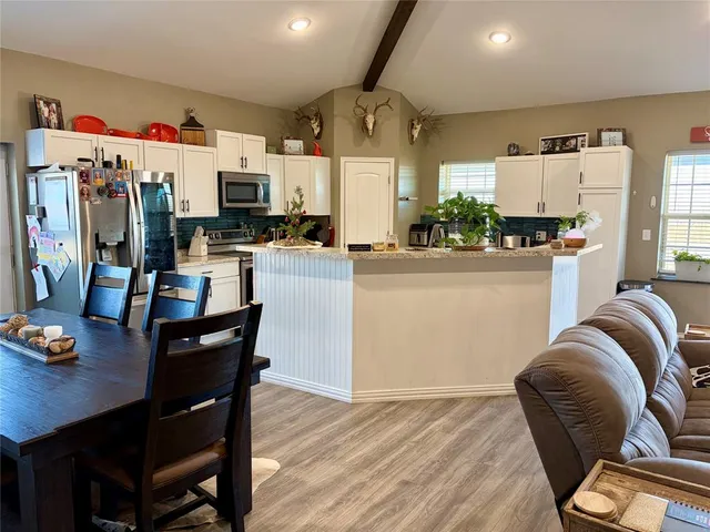 a kitchen with stainless steel appliances granite countertop a refrigerator a stove a sink dishwasher and a dining table with the kitchen view