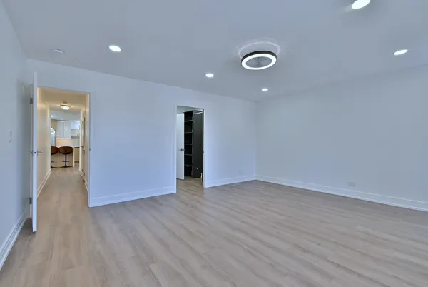 a view of an empty room with wooden floor and a bathroom