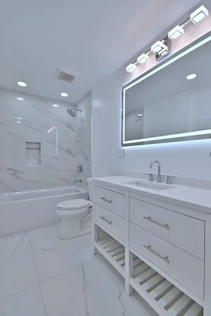 a bathroom with a toilet a sink a mirror a bathtub and vanity