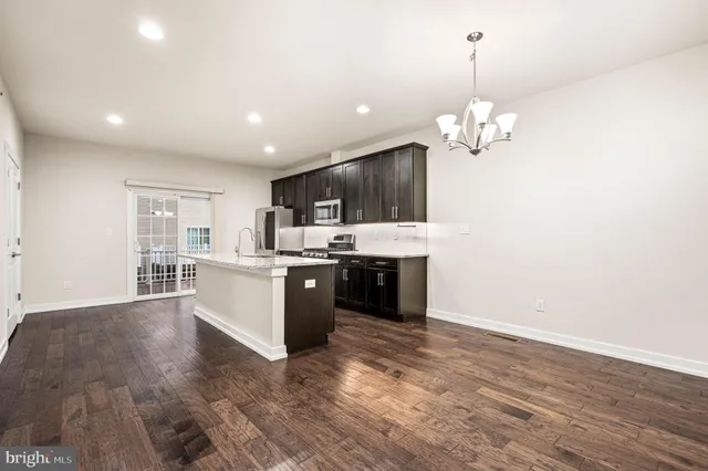 a large kitchen with stainless steel appliances granite countertop a large center island and a wooden floors