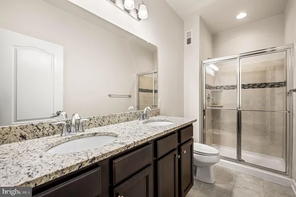 a bathroom with a granite countertop sink a toilet and shower