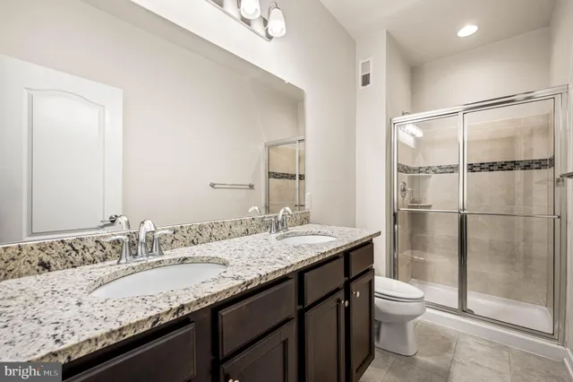 a bathroom with a granite countertop sink a toilet and shower