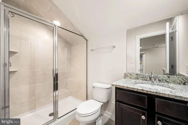a bathroom with a granite countertop sink toilet and shower