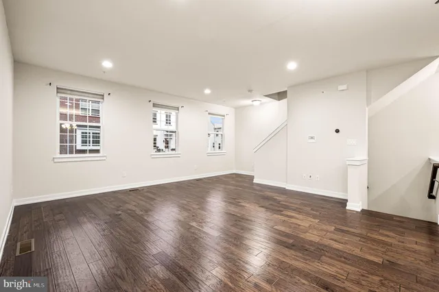 an empty room with wooden floor and windows