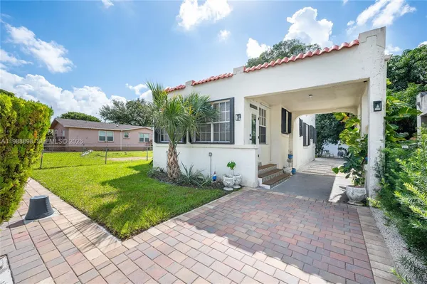 a view of a house with a big yard potted plants and a table