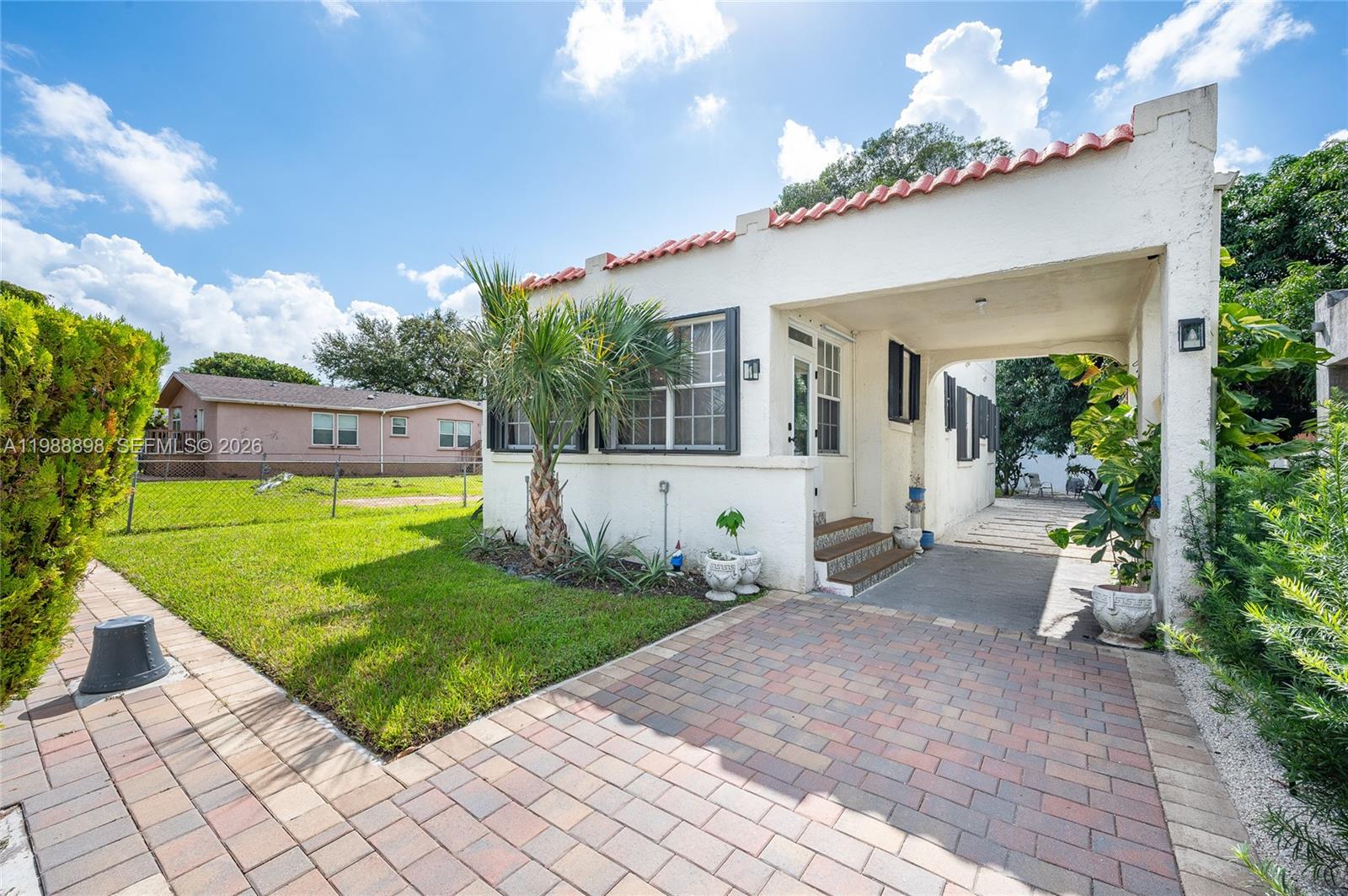 a view of a house with a big yard potted plants and a table