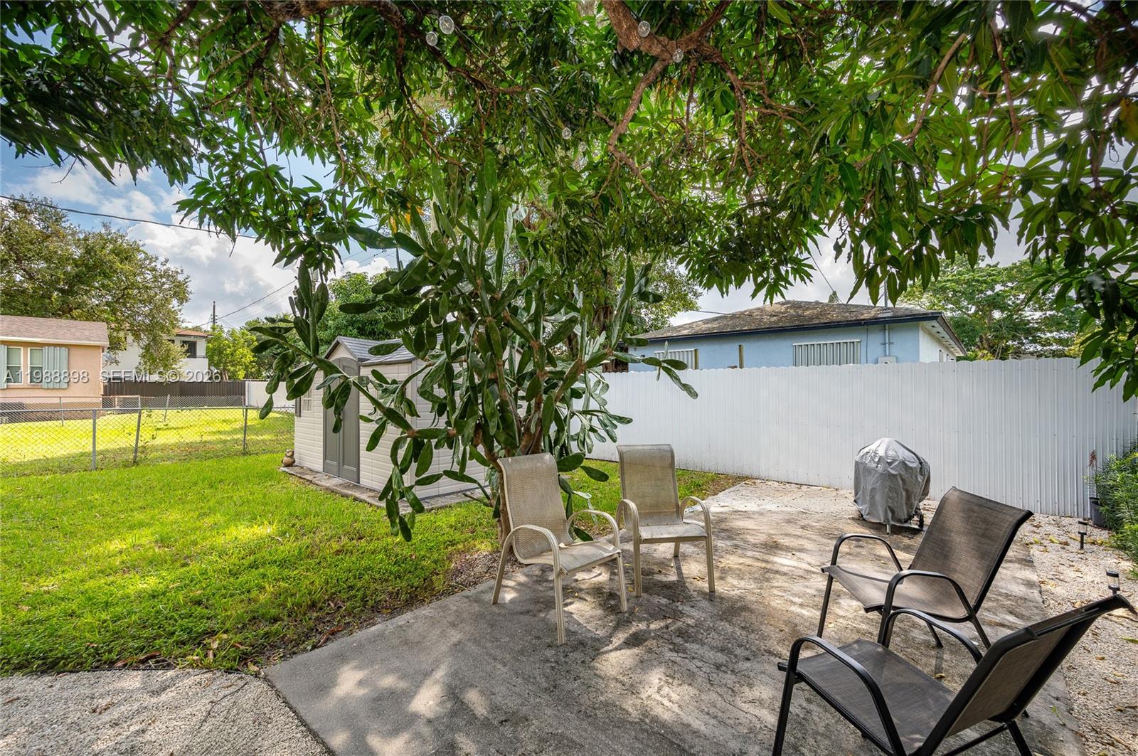 1844 Northwest 47th Street Miami, FL 33142 - Photo 11 of 24 a view of a backyard with table and chairs potted plants and wooden fence
