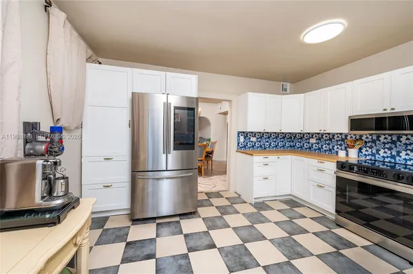 a kitchen with a checkered floor and white stainless steel appliances