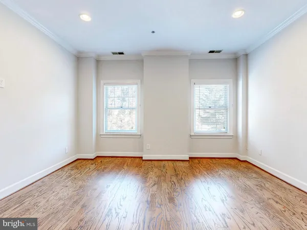 an empty room with wooden floor and windows