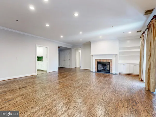 an empty room with wooden floor fireplace and windows