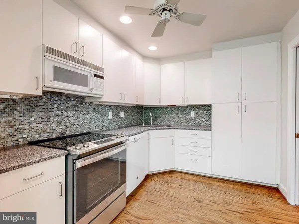 a kitchen with granite countertop white cabinets and white appliances