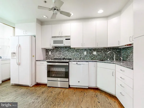 a kitchen with stainless steel appliances white cabinets and a refrigerator