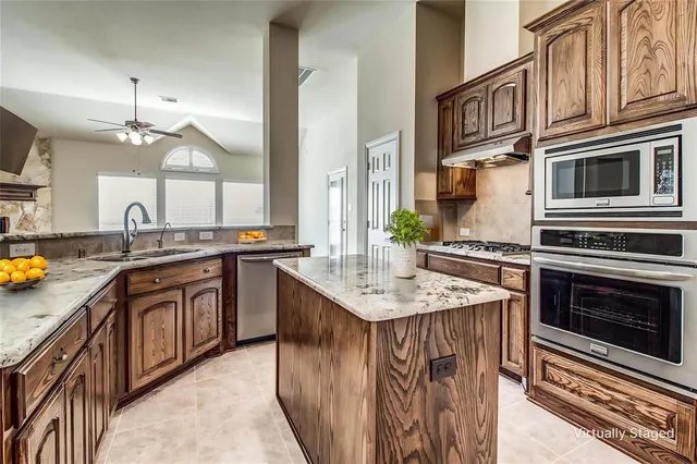 a kitchen with stainless steel appliances kitchen island granite countertop a sink stove and cabinets