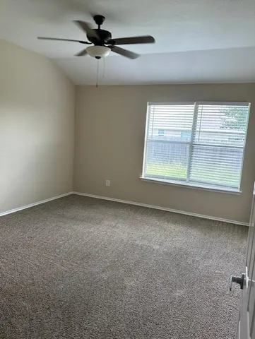 an empty room with a window and a ceiling fan