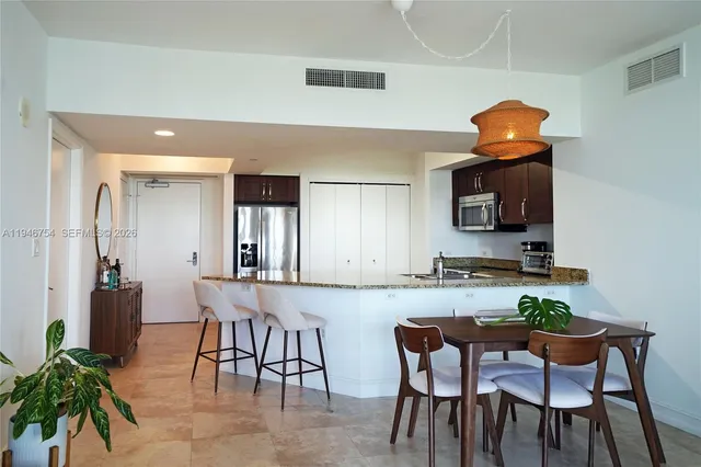 a kitchen with granite countertop kitchen island stainless steel appliances a table and chairs in it