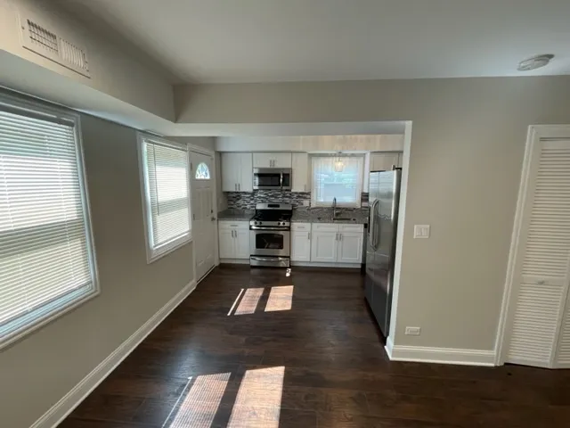 a view of a kitchen with wooden floor and electronic appliances