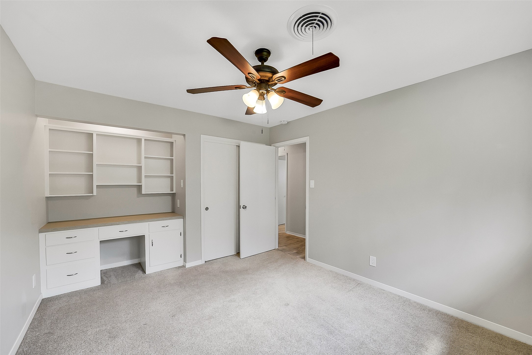 10135 Knoboak Drive Houston, TX 77080 - Photo 20 of 26 Another view secondary bedroom #2 highlighting the built-in desk with pull-out drawers, storage, and shelves above. A sliding door closet with shelving and hanging space completes the room, making it a functional and flexible retreat for a bedroom, study, or playroom.