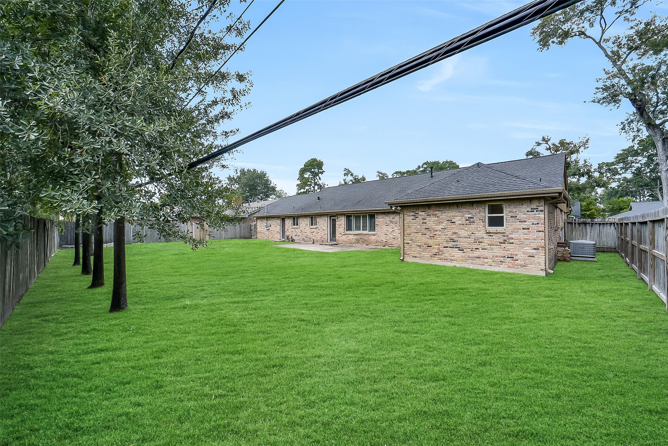 10135 Knoboak Drive Houston, TX 77080 - Photo 26 of 26 Another look at the backyard highlighting the generous greenspace and full view of the home looking from the corner of the fence. Mature trees frame the yard, while the patio area offers a seamless extension of indoor living to the outdoors. Tons of room for kids to play!