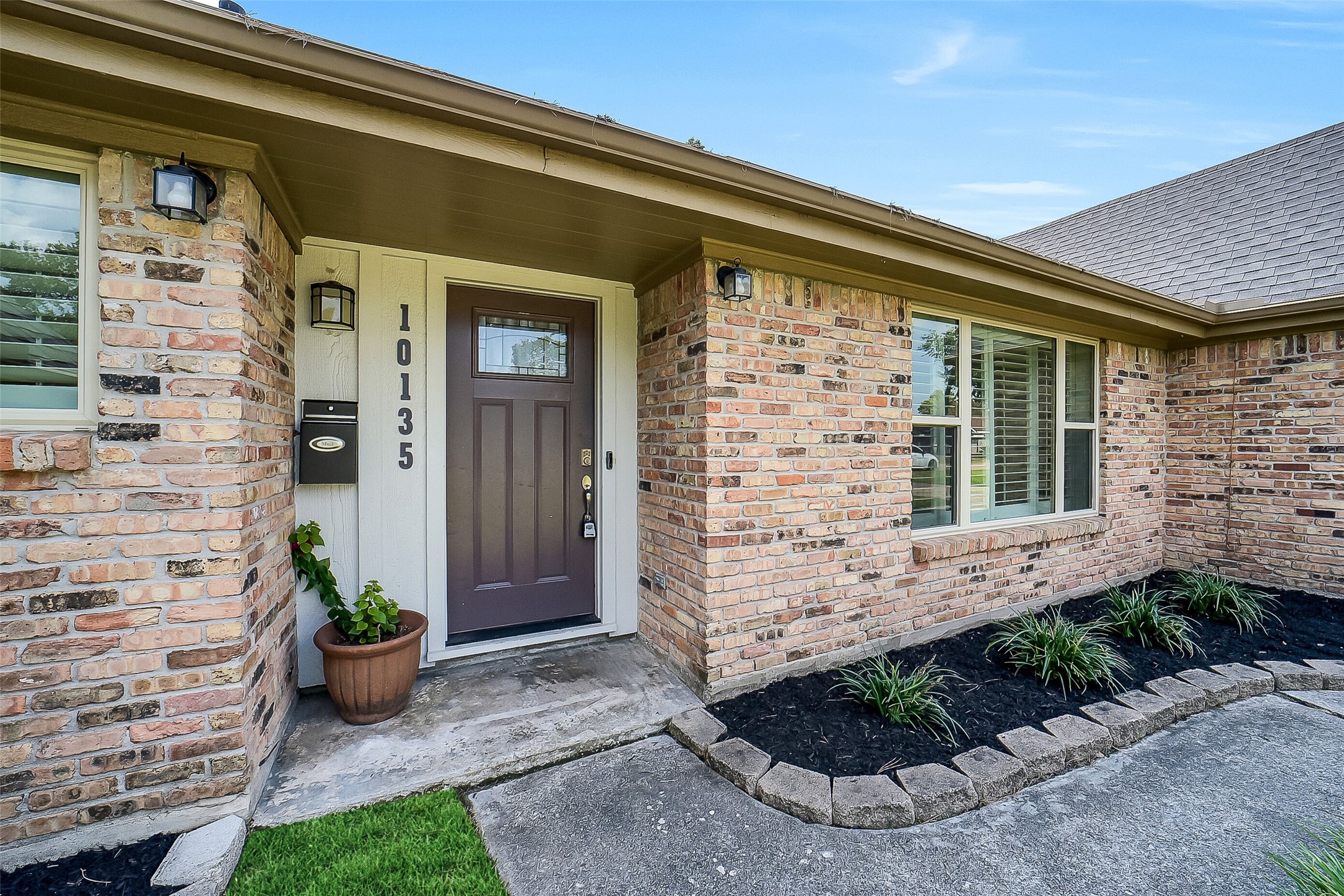 10135 Knoboak Drive Houston, TX 77080 - Photo 3 of 26 Inviting front entry framed by refreshed landscaping and fresh mulch, creating a neat and welcoming first impression. The solid wood door and covered porch provide a warm introduction to the home’s comfortable interior. The classic brick façade and manicured landscaping provide timeless curb appeal.