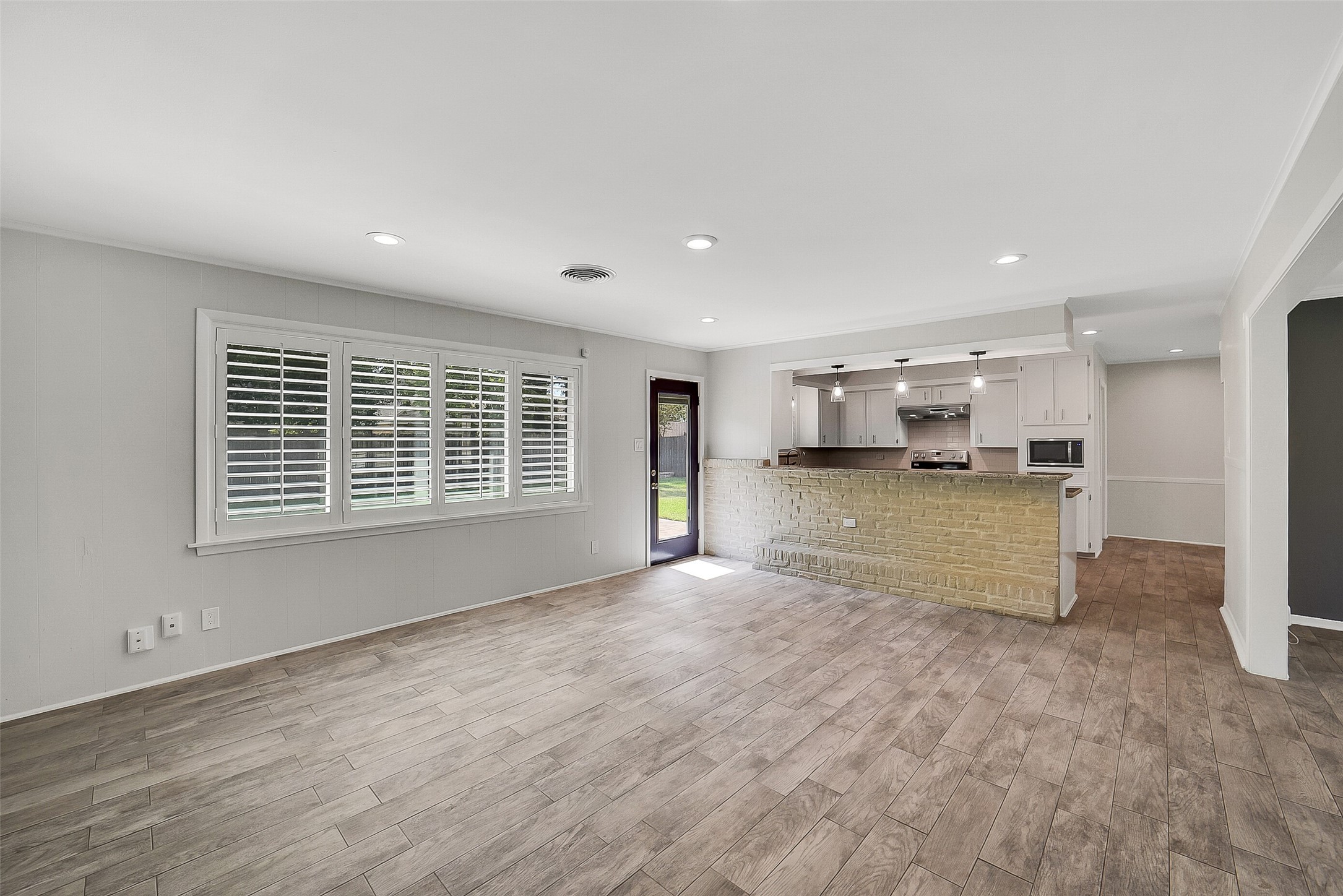 10135 Knoboak Drive Houston, TX 77080 - Photo 9 of 26 A view looking from the family room towards the kitchen. Light filled room w/windows with plantation shutters and door leading to the backyard. Notice the wide peninsula with a brick base separating the kitchen from the living room, creating a natural division while maintaining open flow.