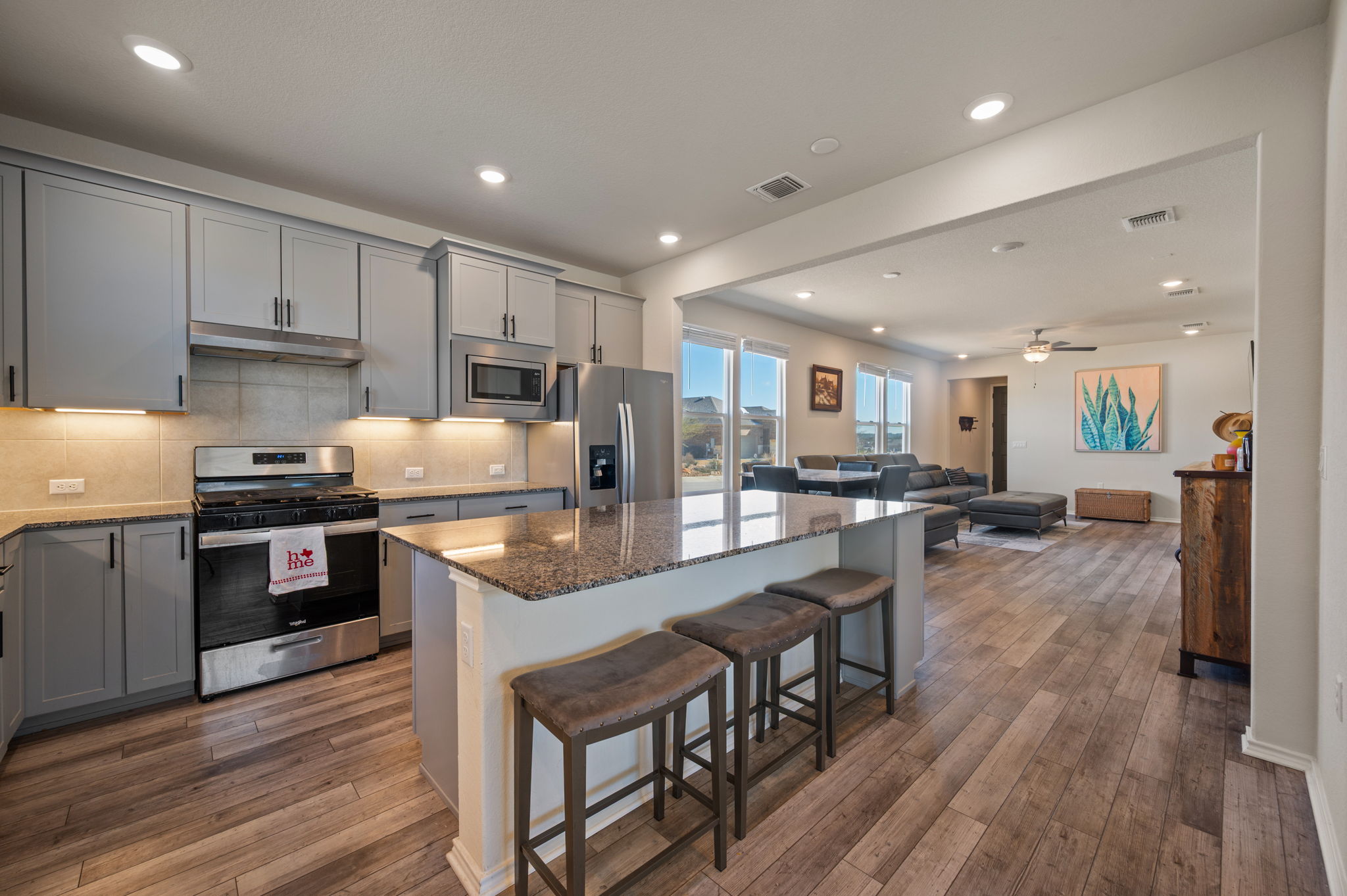 100 Bristol Cove Georgetown, TX 78633 - Photo 6 of 31 a kitchen with kitchen island granite countertop wooden floors and stainless steel appliances