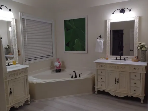 a bathroom with a tub a double vanity sink and mirror