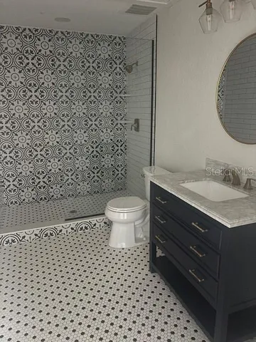 a bathroom with a granite countertop toilet a sink and a mirror