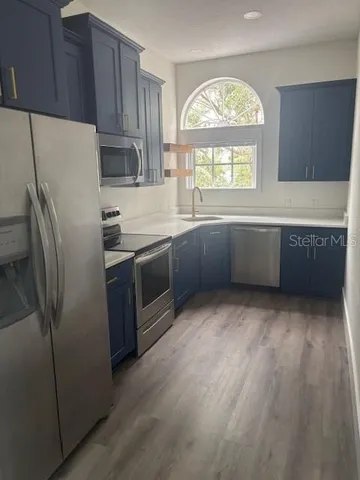 a kitchen with stainless steel appliances granite countertop a refrigerator a sink a stove and a refrigerator