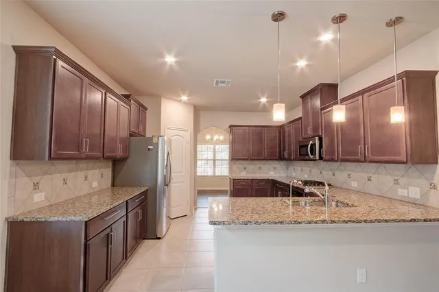 a kitchen with stainless steel appliances granite countertop a sink refrigerator and microwave