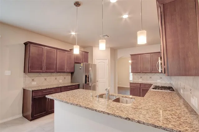 a kitchen with kitchen island granite countertop a sink a counter top space appliances and cabinets