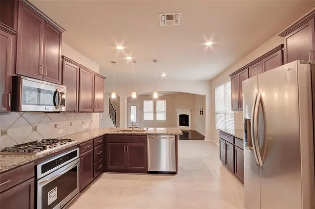 a kitchen with stainless steel appliances granite countertop a stove a sink and a refrigerator
