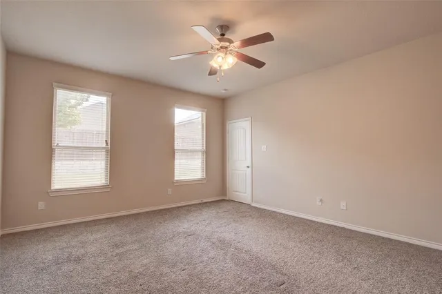 an empty room with chandelier fan and windows