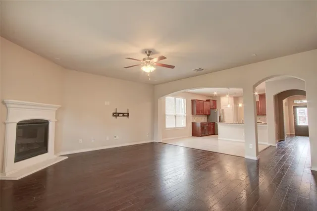 a view of an empty room with chandelier fan and wooden floor