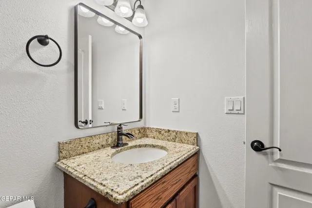 a bathroom with a granite countertop sink and a mirror