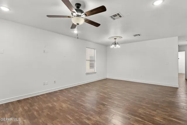an empty room with wooden floor ceiling fan and window