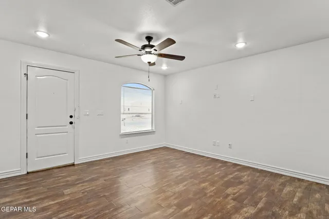 an empty room with a window and a fan