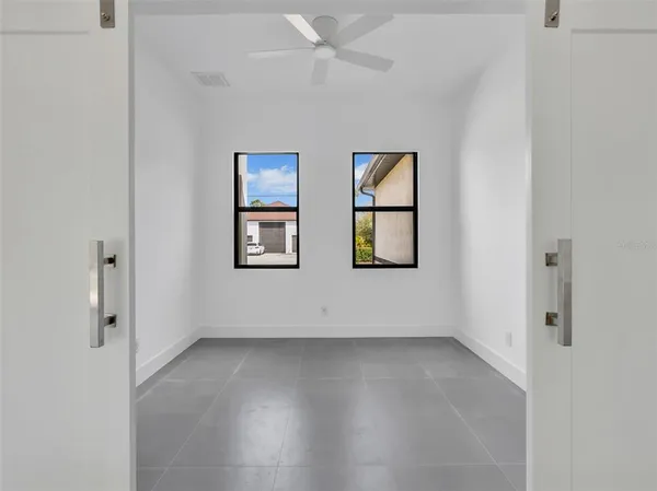 an empty room with windows and ceiling fan