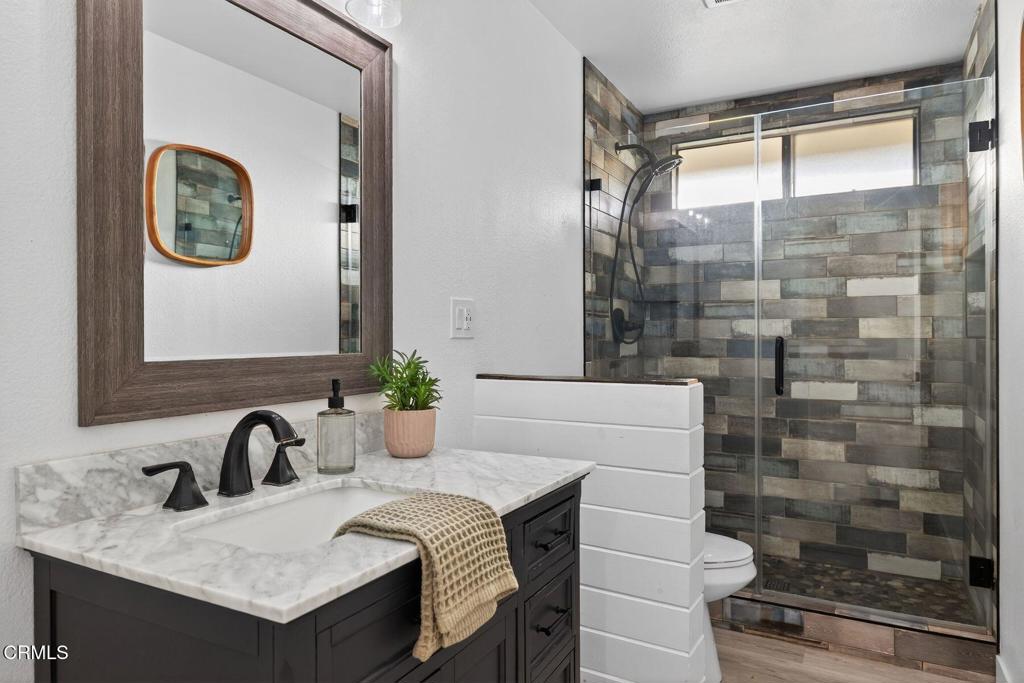 4975 North Buttercreek Road Moorpark, CA 93021 - Photo 33 of 47 a bathroom with a granite countertop sink a mirror and a shower