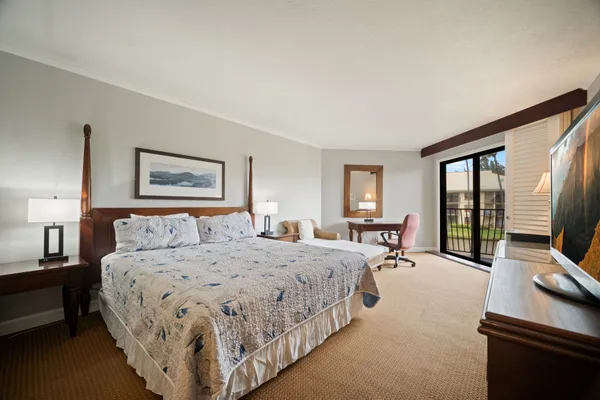 a bedroom with a bed a couch and a flat tv screen on a dresser