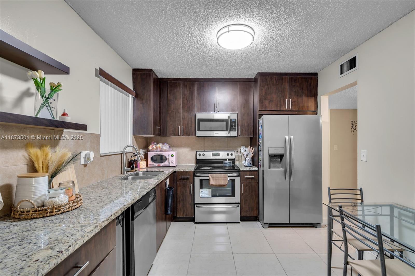 451 Ives Dairy Road, Unit 1031 Miami, FL 33179 - Photo 5 of 29 a kitchen with stainless steel appliances granite countertop a sink a stove and a refrigerator