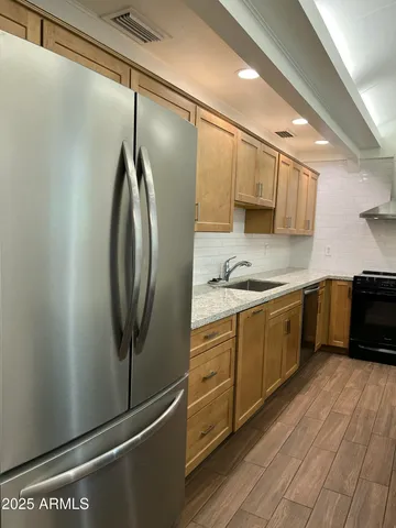 a kitchen with stainless steel appliances granite countertop a refrigerator a sink dishwasher a stove and white countertops with wooden floor