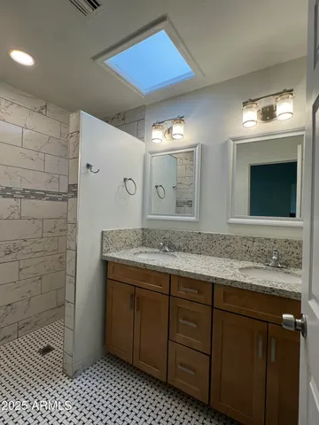 a bathroom with a granite countertop sink a mirror and a shower