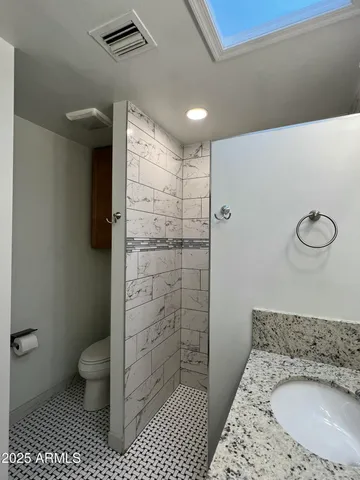 a bathroom with a granite countertop sink a toilet and shower