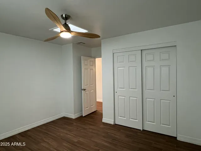 an empty room with wooden floor cabinet and windows