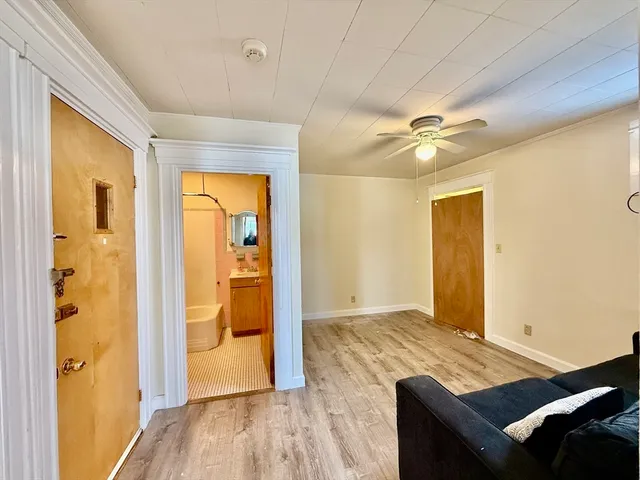 a view of an empty room with wooden floor and a window