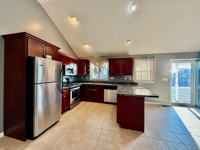 a large kitchen with a large counter top a refrigerator and a sink