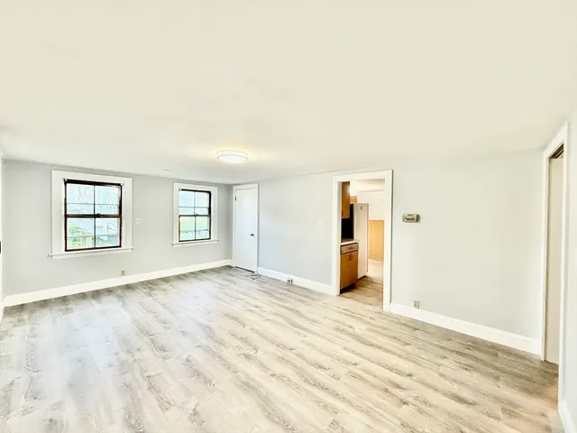 a view of an empty room with window and wooden floor