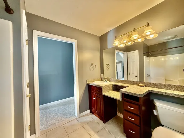 a bathroom with a granite countertop sink a toilet and a mirror