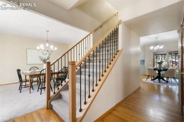 a view of a hallway with wooden floor table and chairs